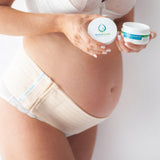 A pregnant woman holding a container of BellyBands stretch mark and scar cream