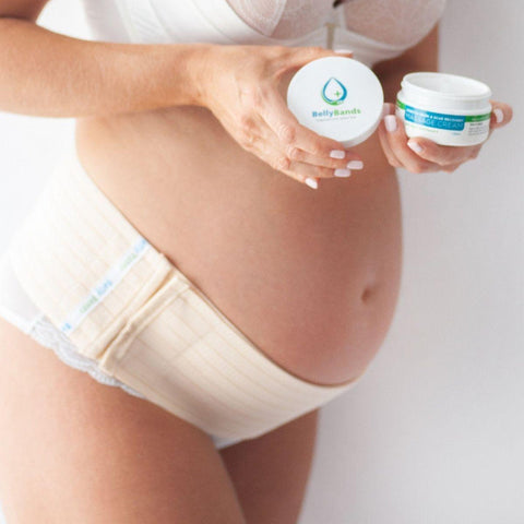 A pregnant woman holding a container of BellyBands stretch mark and scar cream