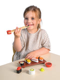 Child playing with a toy sushi set on a white background